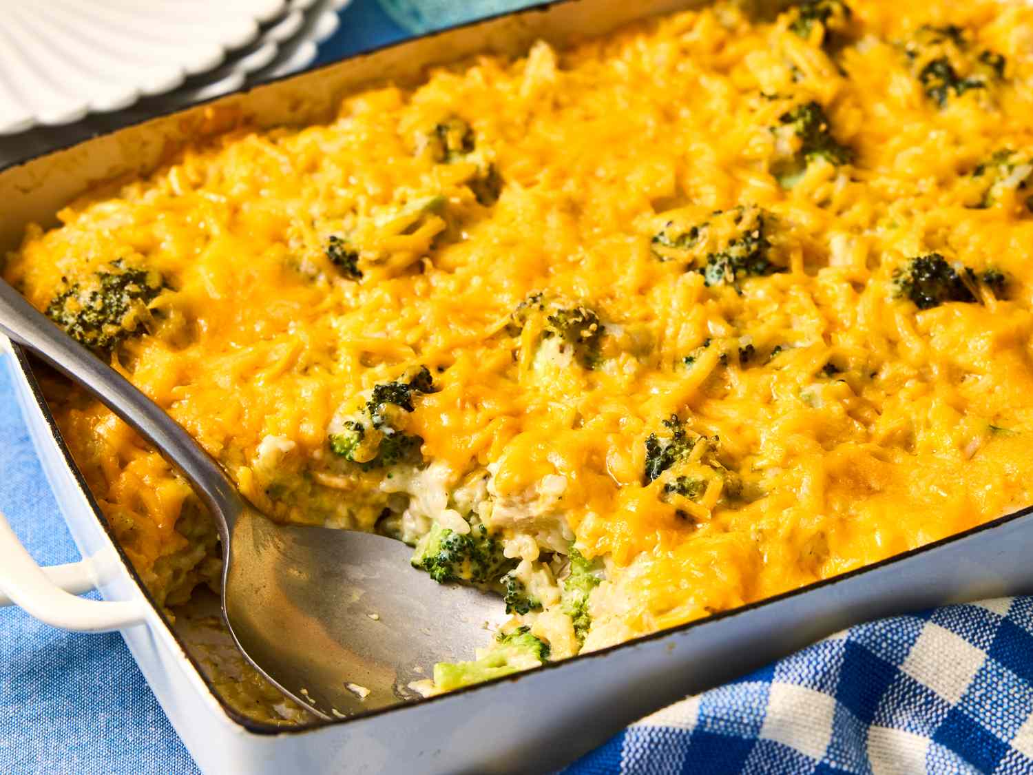 A baked broccoli rice casserole with chicken in a ceramic dish, bubbling at the edges with a golden cheesy top on a wooden table
