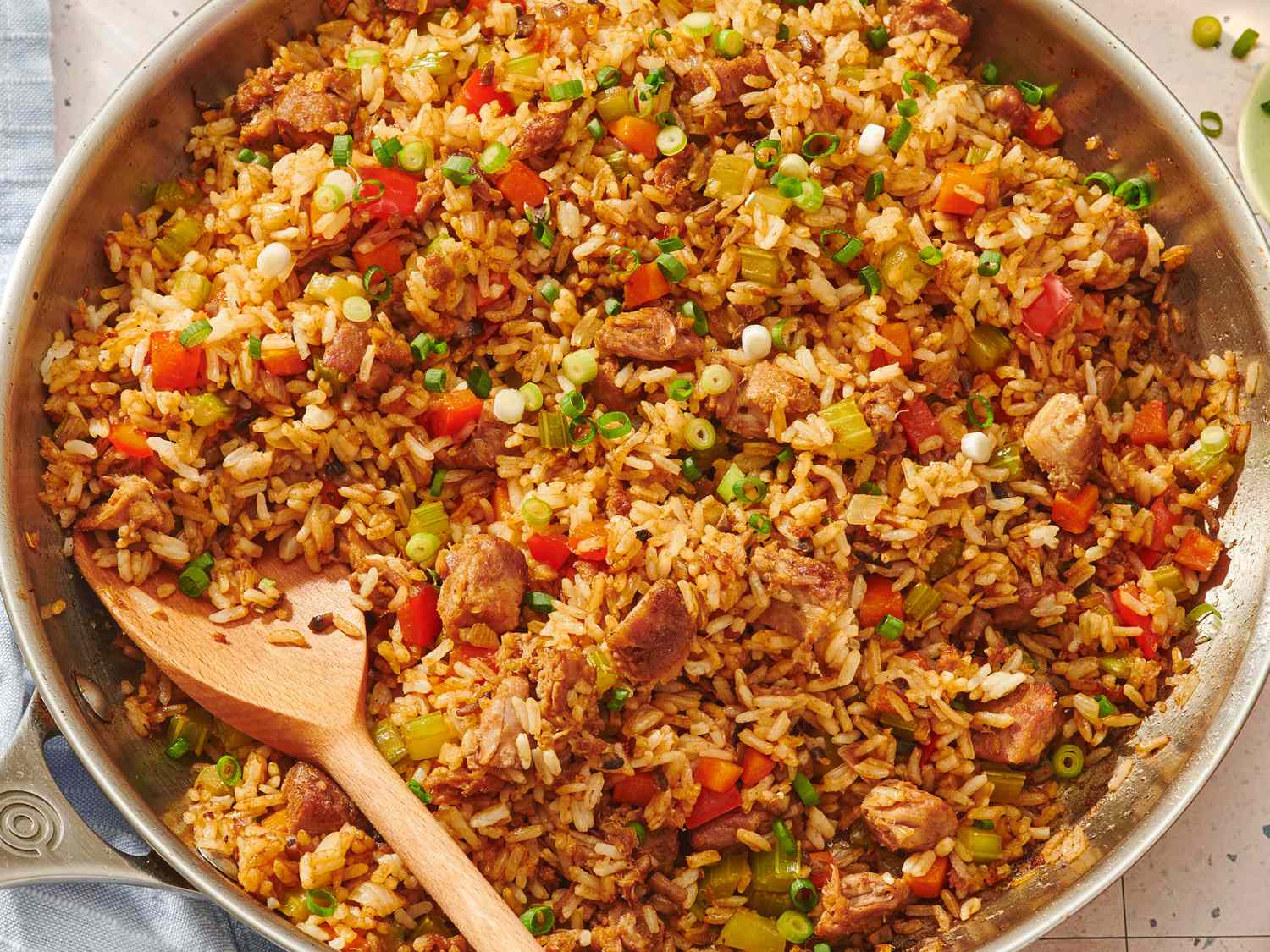 A steaming skillet of fried rice with visible grains of rice, scrambled egg ribbons, peas, and scallions, set on a kitchen counter