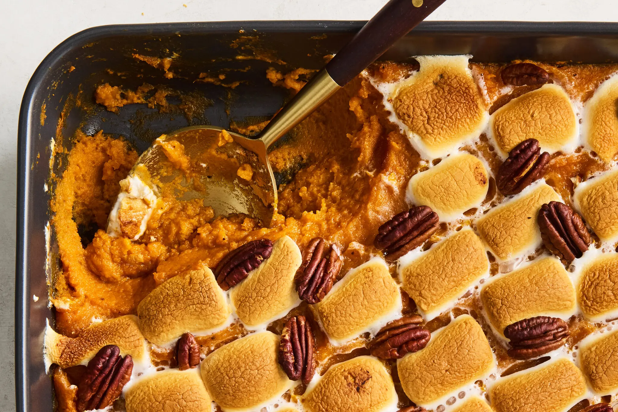 A sweet potato casserole on a holiday table set with plates, linen napkins, and serving utensils, with the casserole as the centerpiece