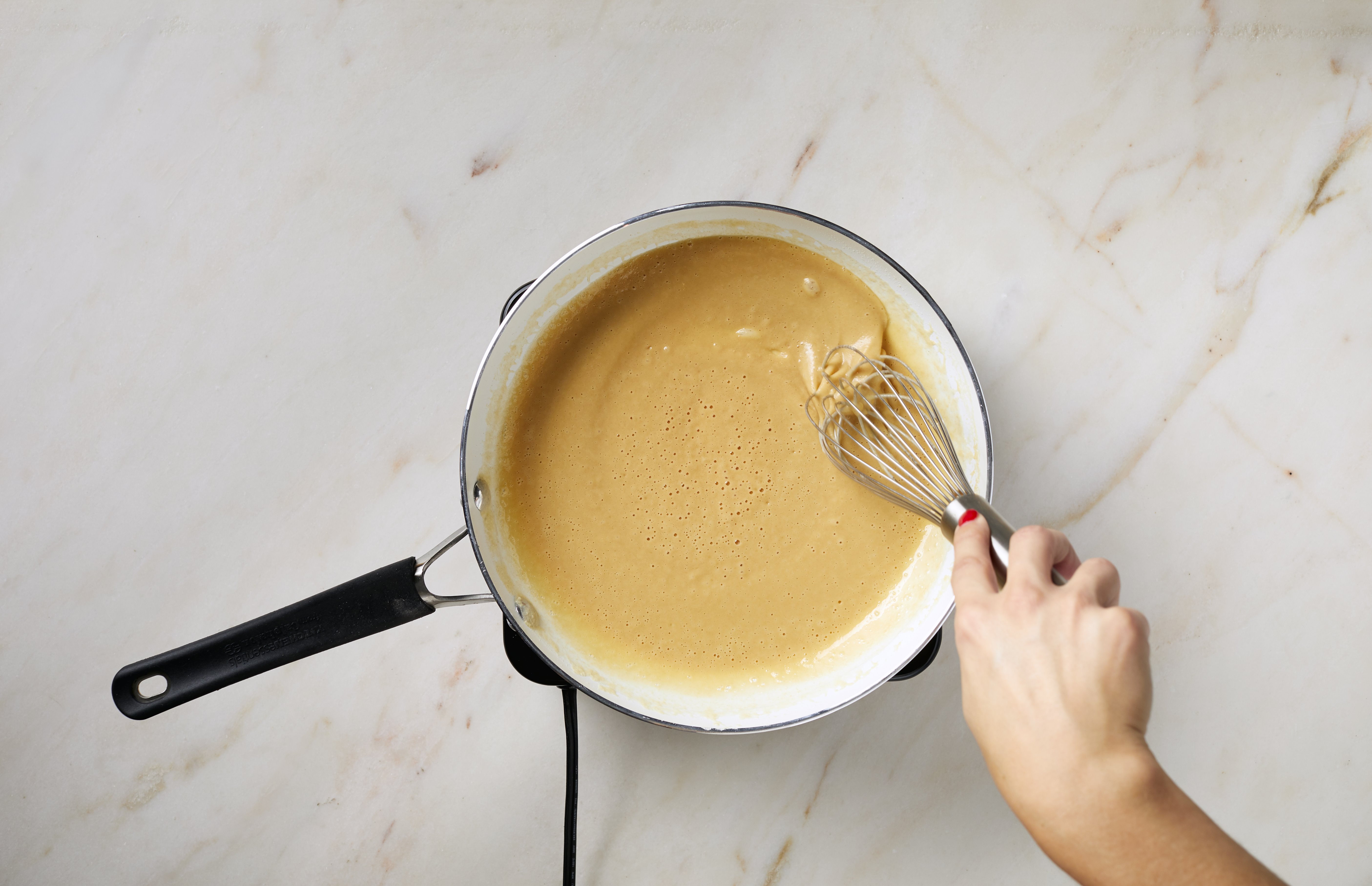 Butter melting in a small saucepan with flour and a whisk nearby on a home kitchen counter