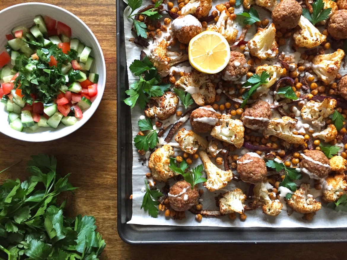 Two sheet pans of evenly spaced turkey meatballs baking in an oven, lightly browned on top with a few browned bits on the pans